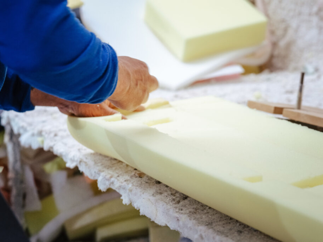 Vertical shot of a furniture maker shaping an upholstery foam